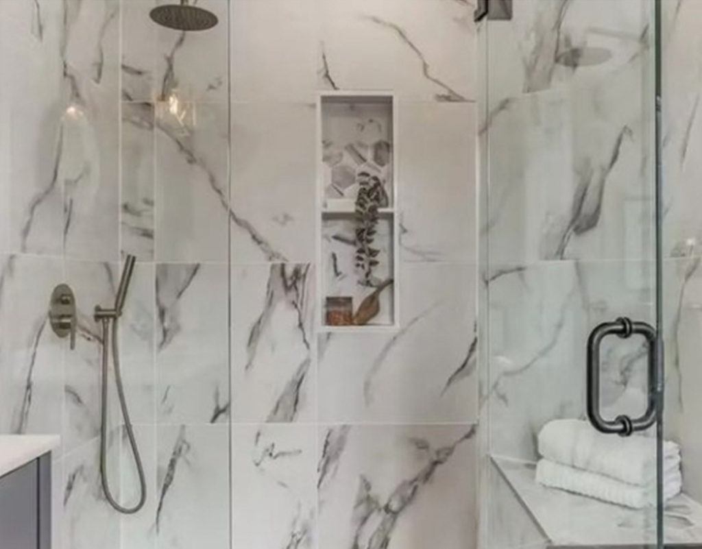 close up shot of a shower with black and white marble and glass doors