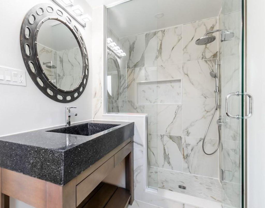 a black marble bathroom vanity with a sink next to a marble shower