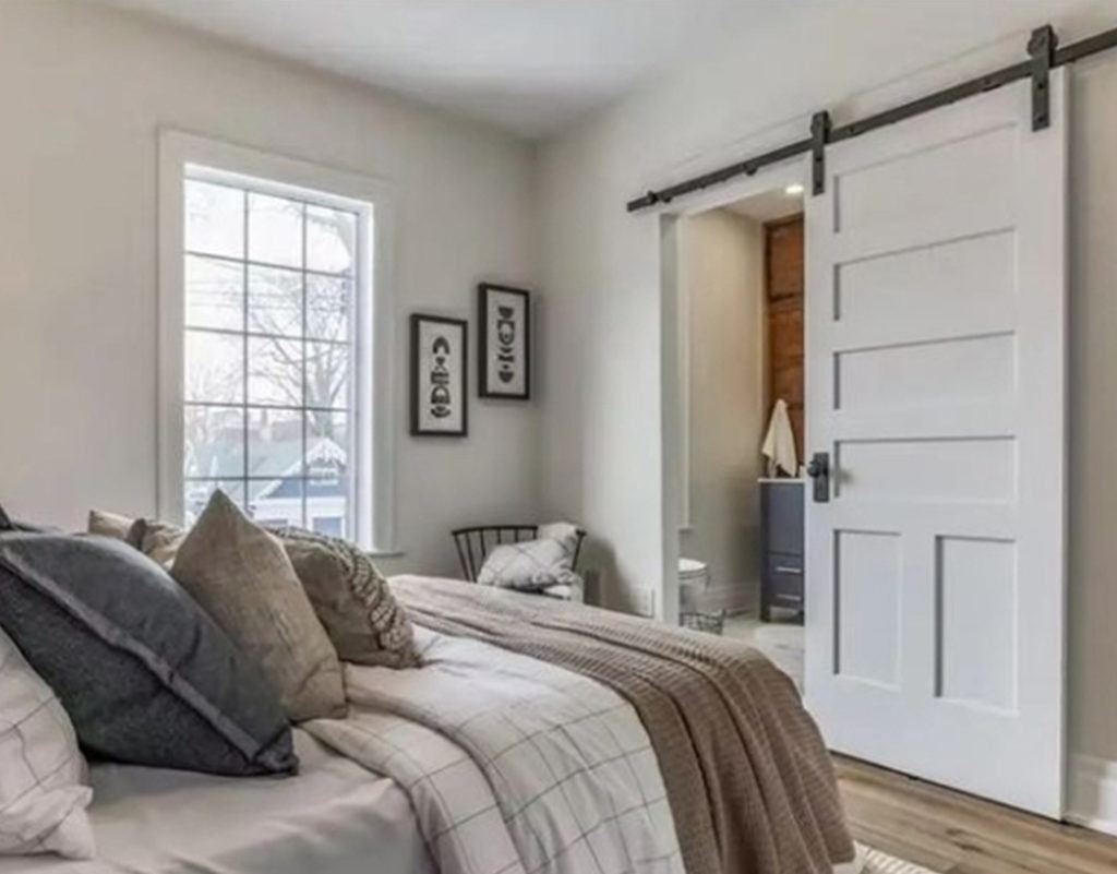 bedroom with a wooden barn door leading to a bathroom