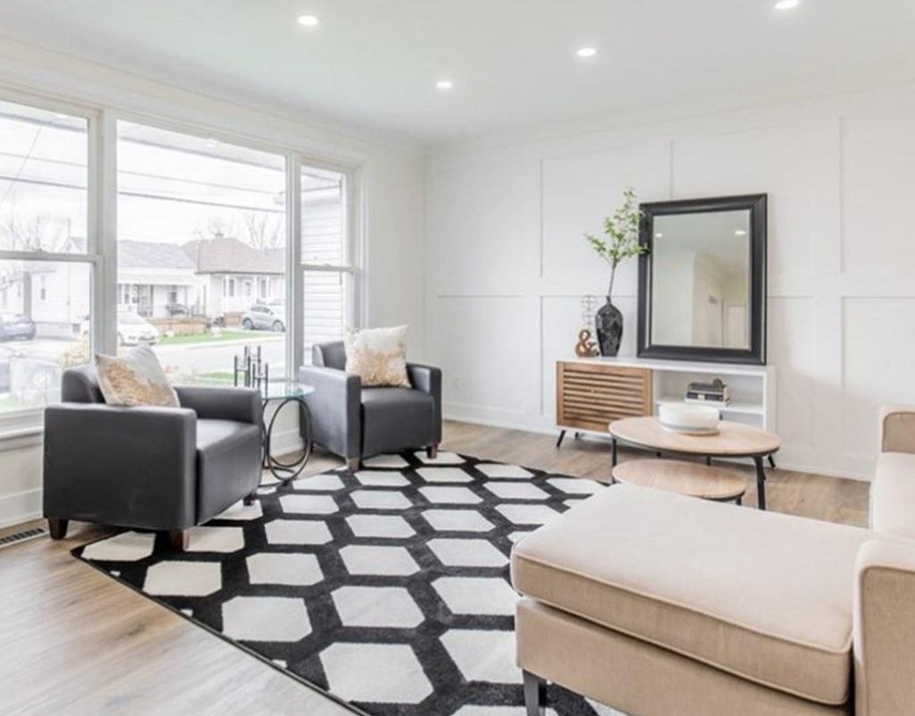 living room with two black leather arm chairs and a black and white area rug