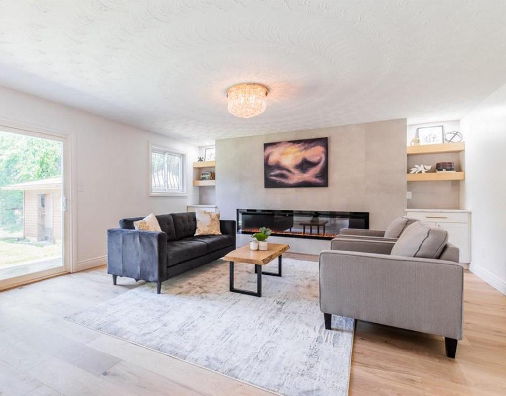 living rooms with a gas fireplace, black sofa and two beige arm chairs