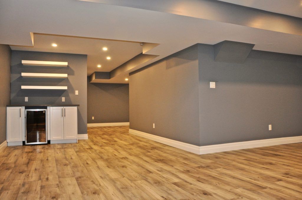 a remodelled basement with hardwood floor and dark grey walls