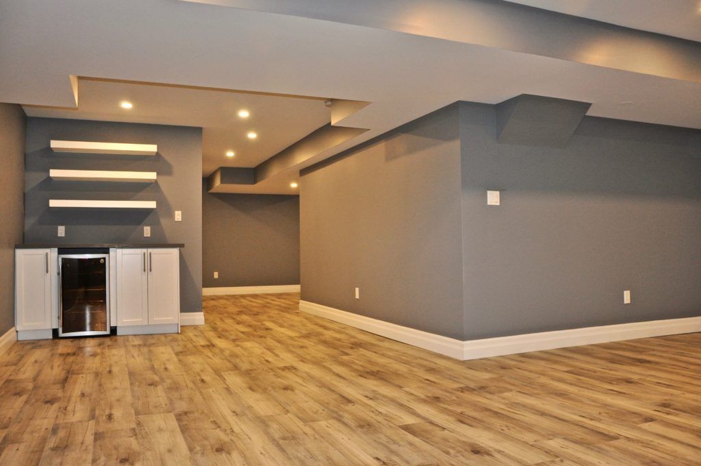 a remodelled basement with hardwood floor and dark grey walls