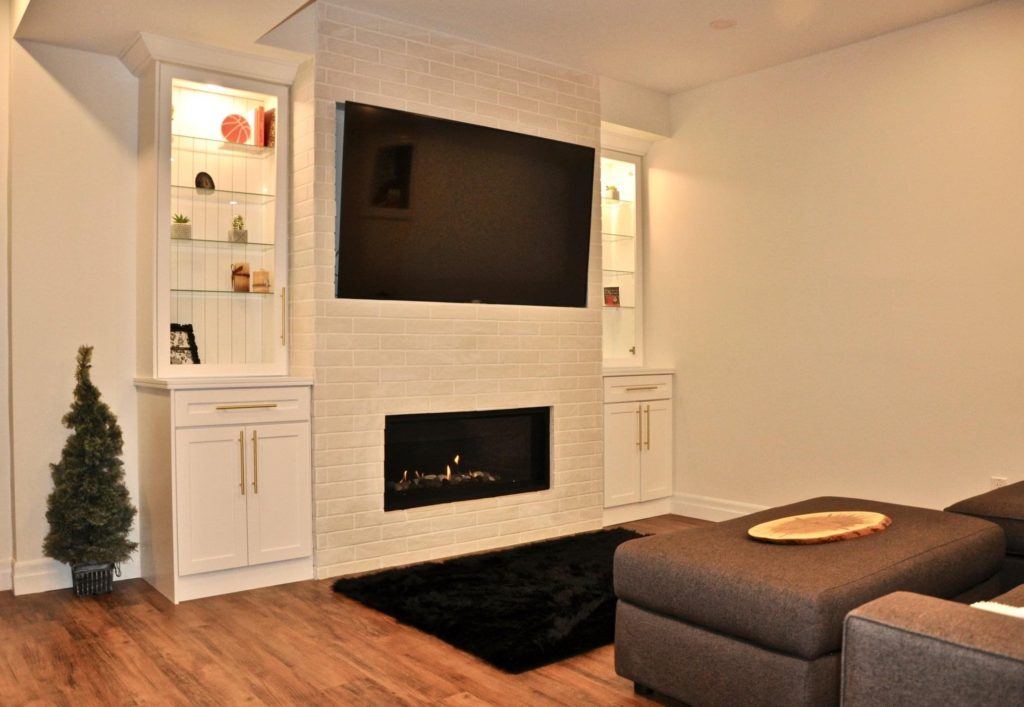 flatscreen television above a gas fireplace in a remodelled basement