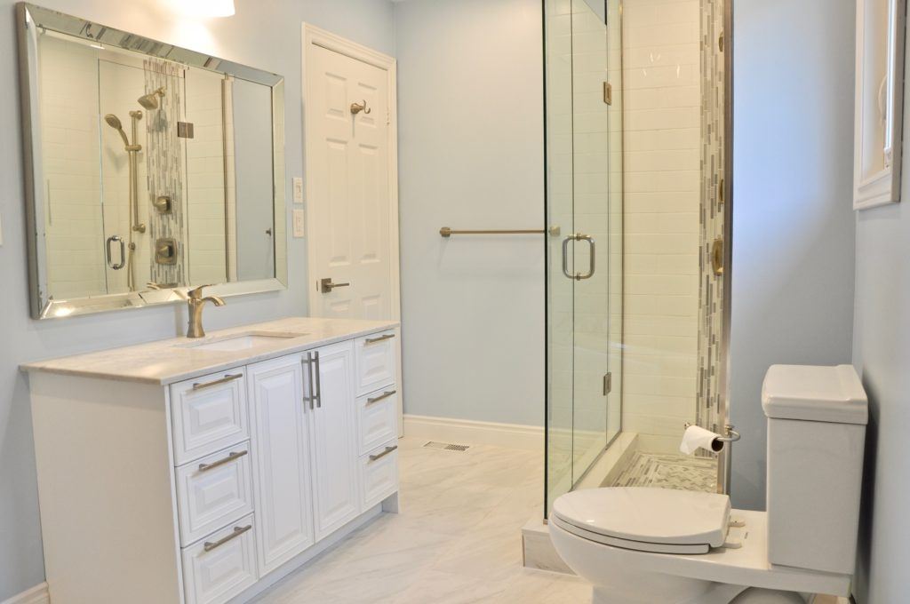 a bathroom with white cabinetry and glass door shower