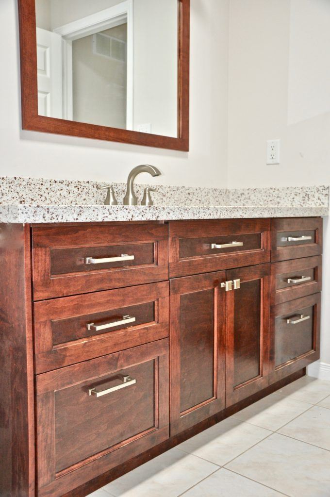 a wooden bathroom vanity with black spotted countertop