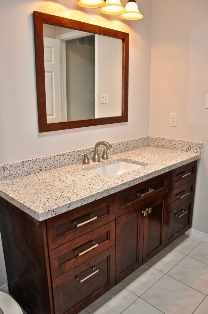 a wooden bathroom vanity with black spotted countertop