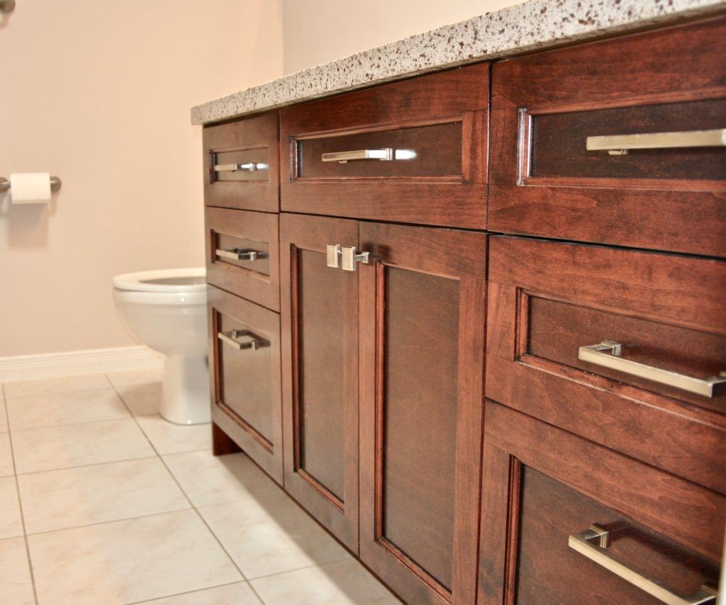 a wooden bathroom vanity with black spotted countertop