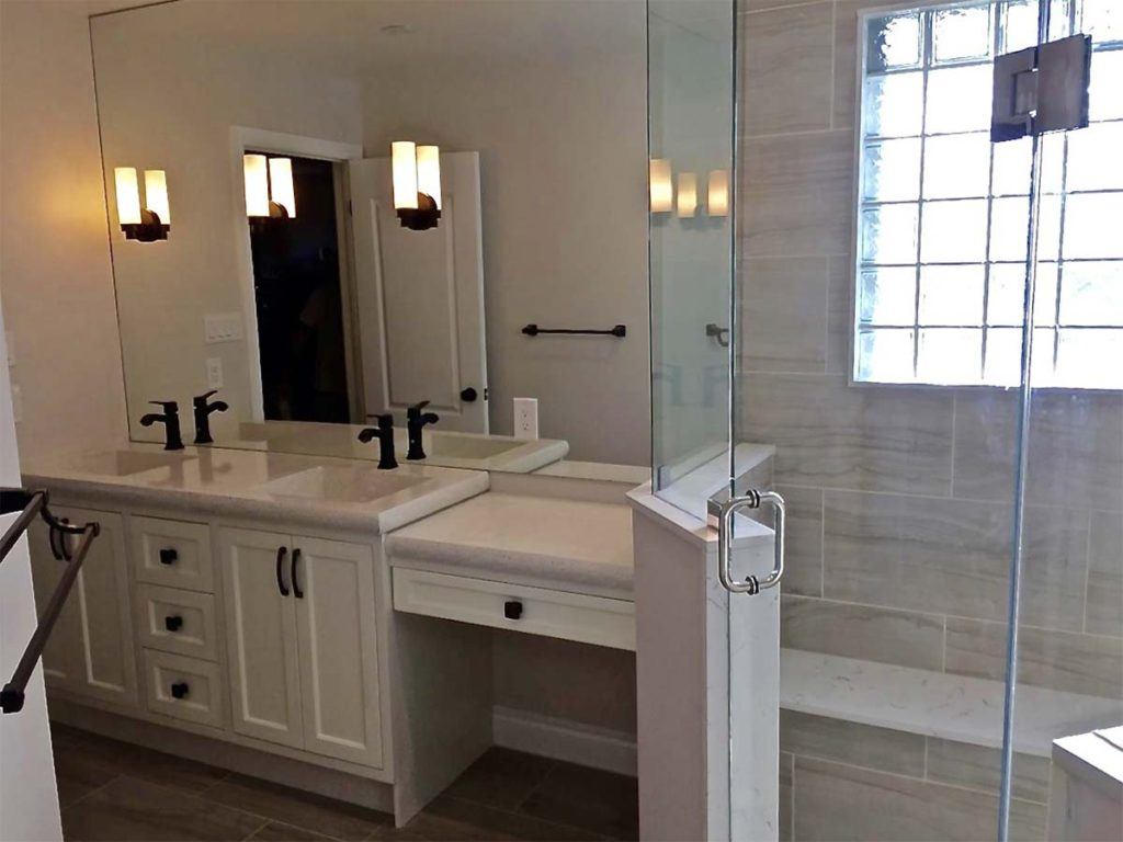 double bathroom sinks in a white vanity next to a glass shower