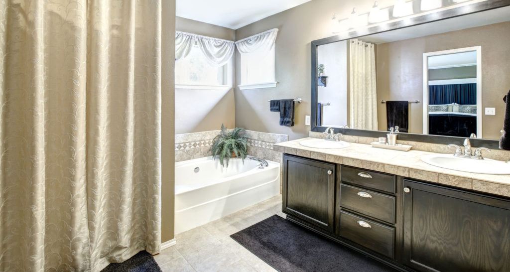 double sinks in a black bathroom vanity next to a bathtub