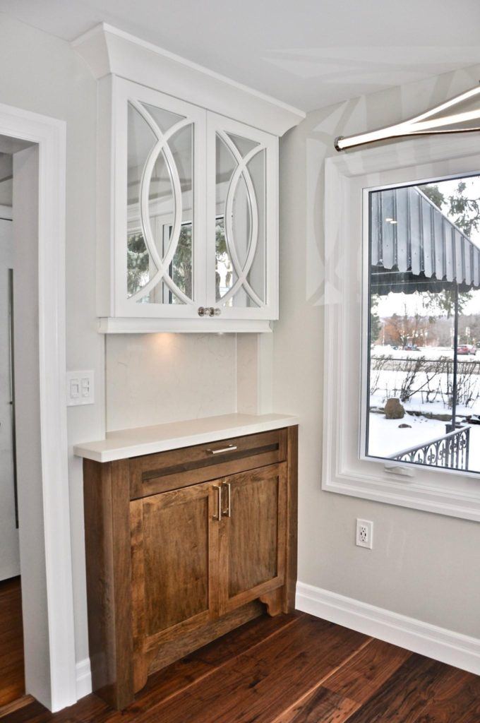 a white cabinet with mirrored doors one a wall