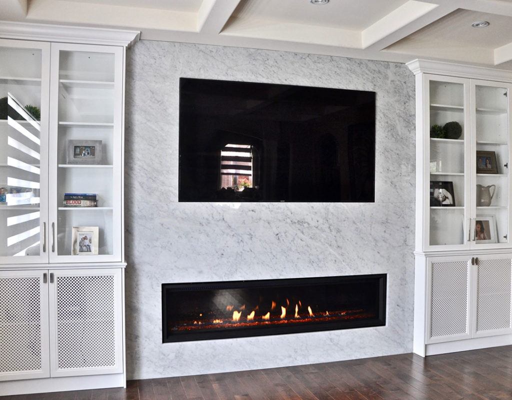 flat screen television surrounded by marble with a gas fireplace underneath